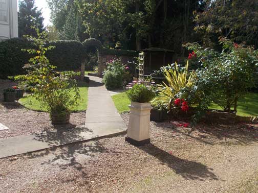view from flower bed pillar across first garden looking through gateway into second large garden